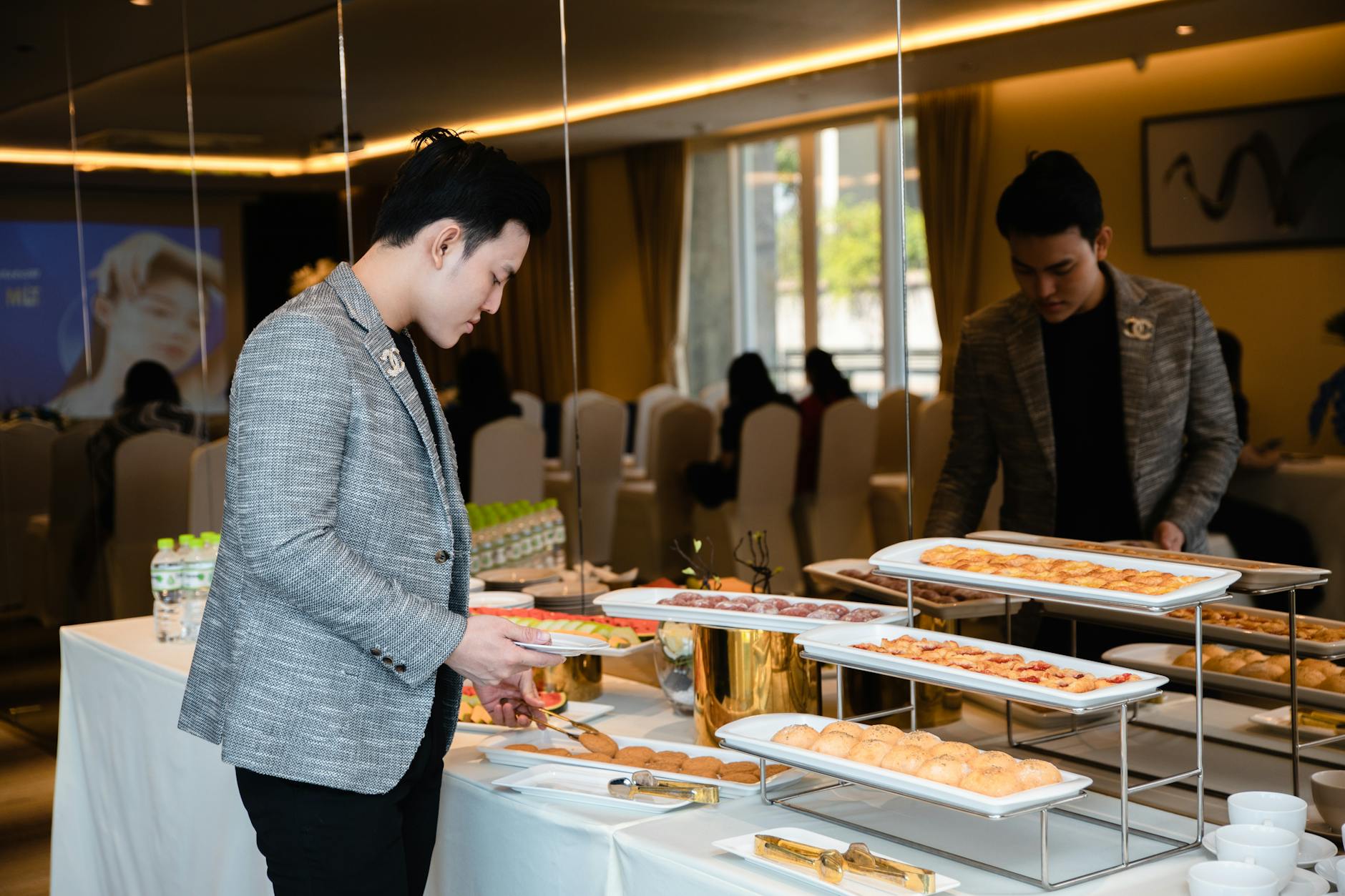 Mężczyzna wybiera miniaturowe ciastka z bufetu na firmowym evencie