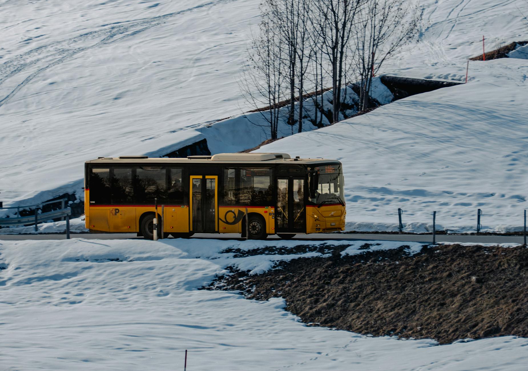 Żółty bus jedzie ośnieżoną górską drogą zimą