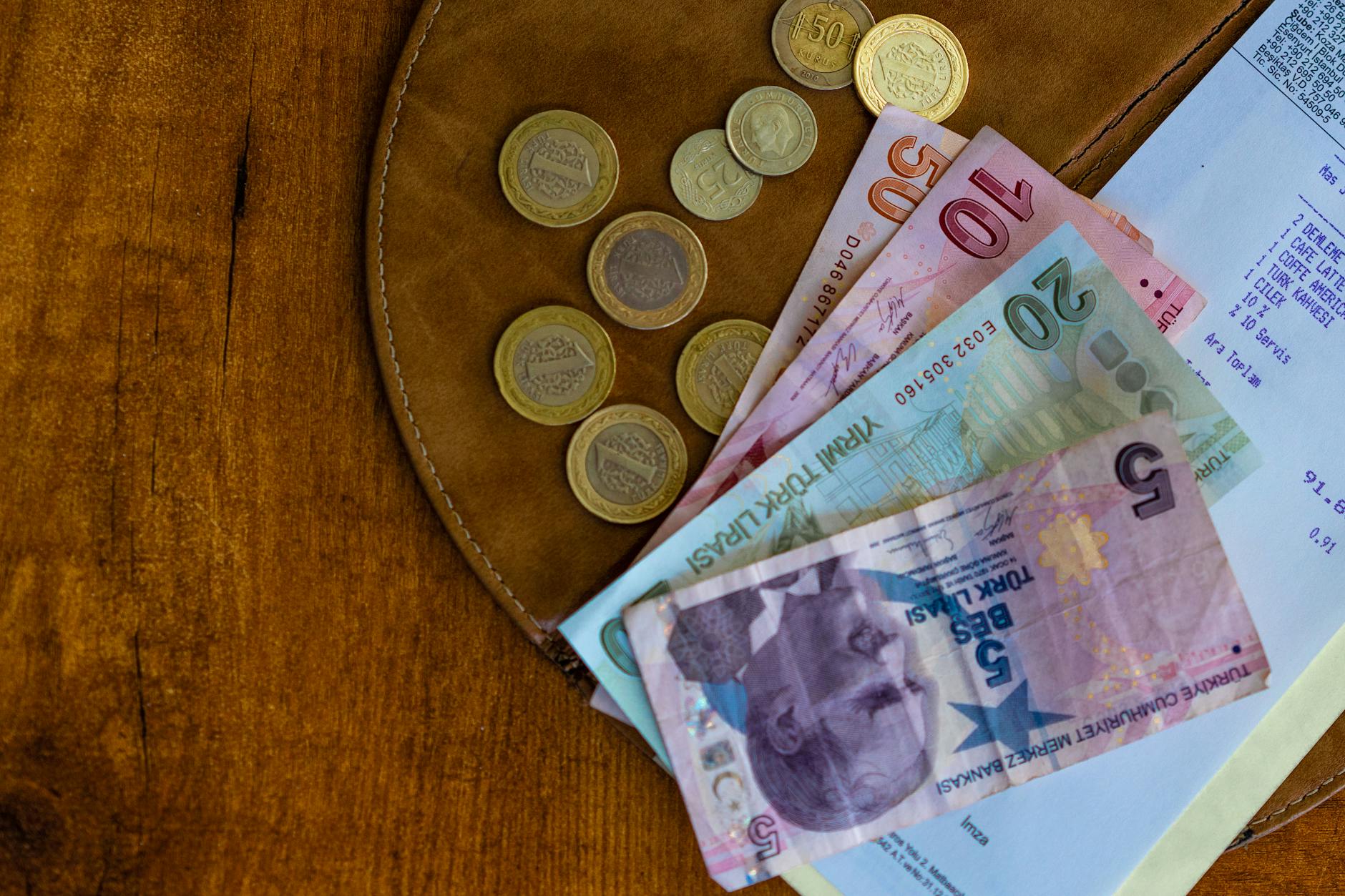 Monety i banknoty tureckiej liry z paragonem na drewnianym blacie