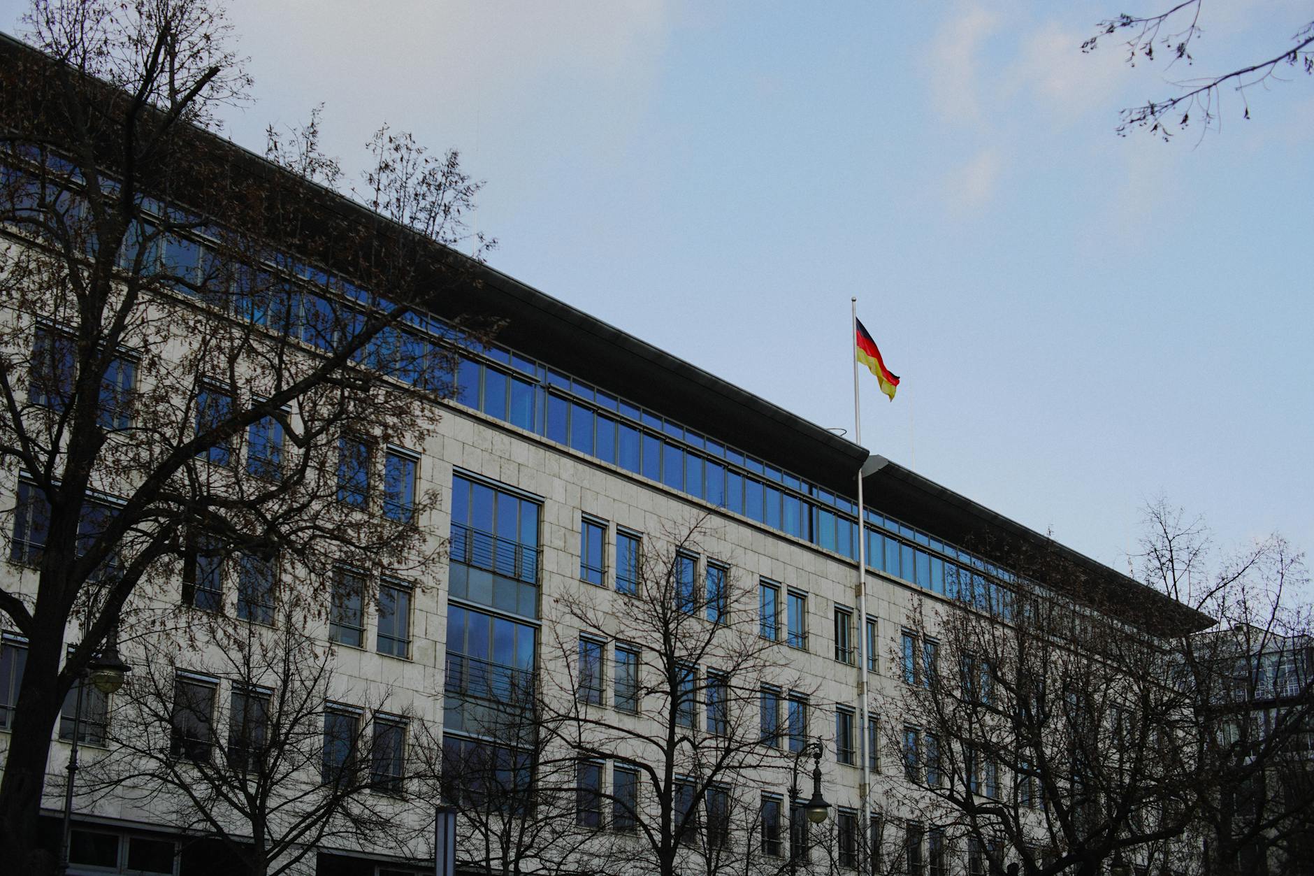 Rejestracja pobytu w Niemczech po przyjeździe co i gdzie załatwić Nowoczesny niemiecki urząd z flagą na tle zimowych drzew