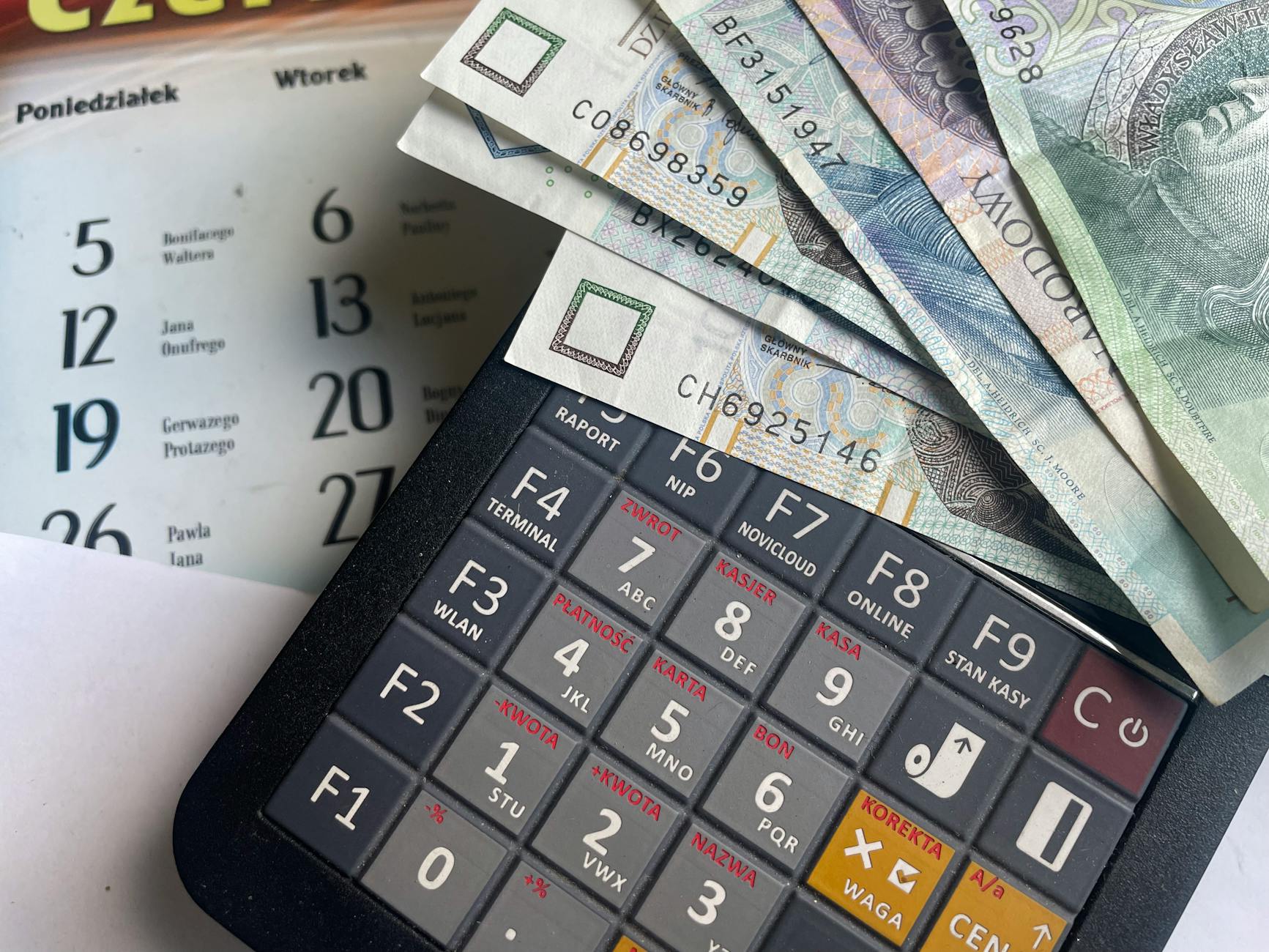 Polskie banknoty na kalkulatorze z kalendarzem w tle