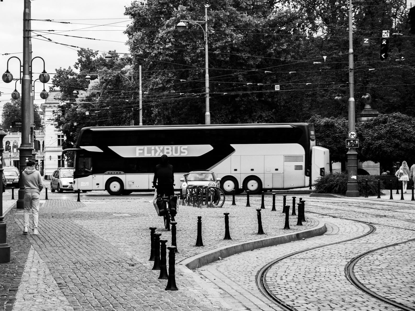 Jak zabrać rower busem do Europy i nie dopłacić fortuny za bagaż Rowerzysta i piesi obok autobusu FlixBus na miejskiej ulicy