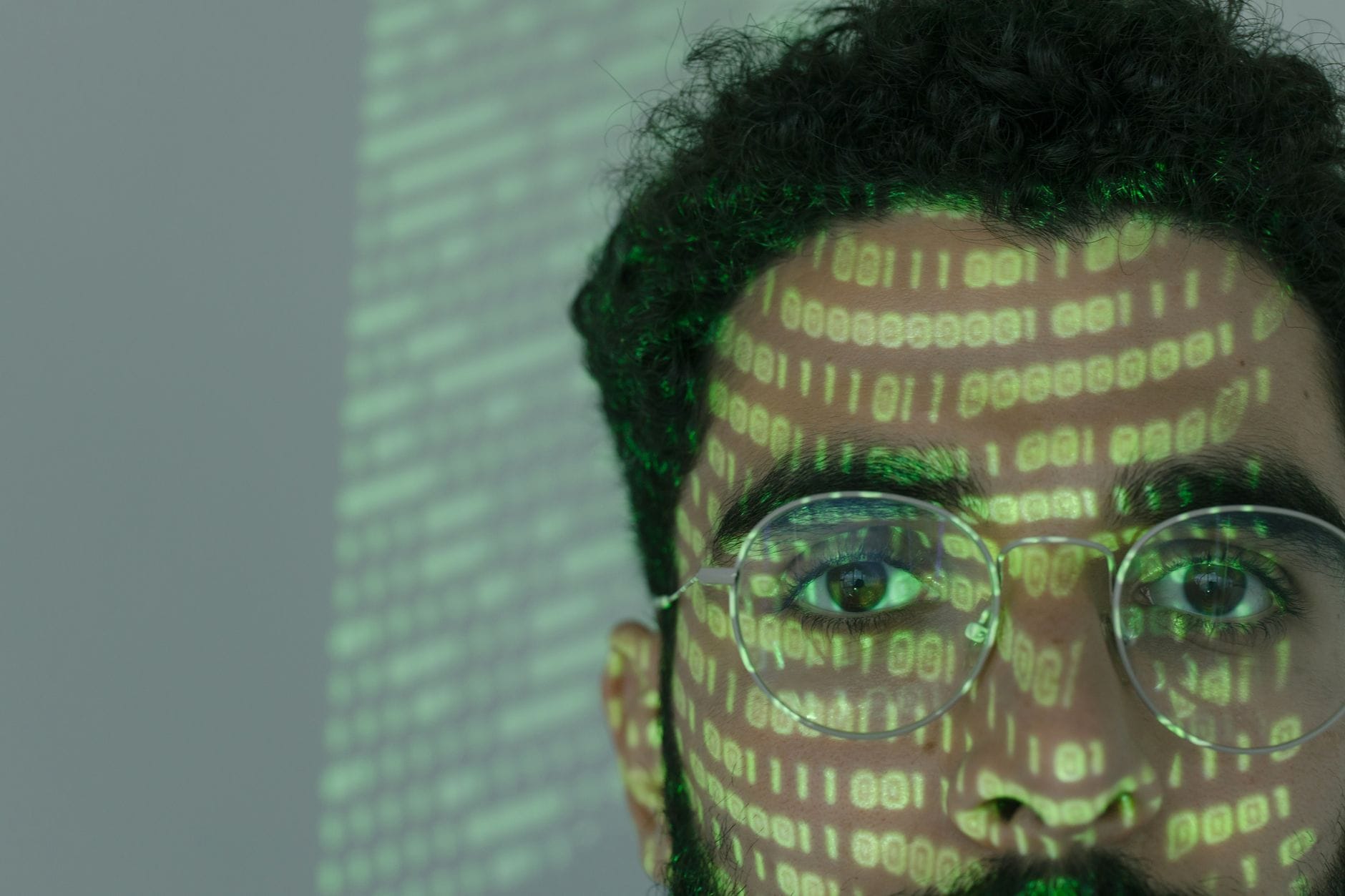 Twarz mężczyzny z nałożonym kodem binarnym symbolizującym cyberbezpieczeństwo
